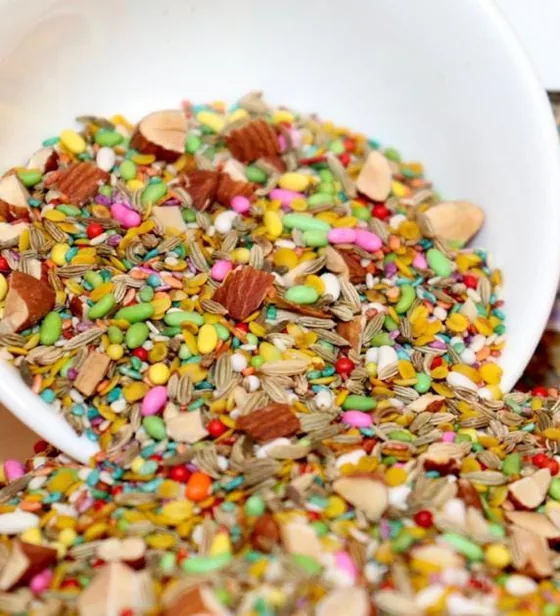 A white bowl spilling over with a colourful sweet seed and almond mix